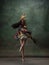 Young graceful tender ballerina on dark green studio background