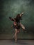 Young graceful tender ballerina on dark green studio background