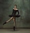 Young graceful tender ballerina on dark studio background