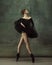 Young graceful tender ballerina on dark studio background