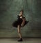 Young graceful tender ballerina on dark studio background