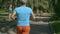 Young grey haired man in blue tshirt runnings along the tropical park road, close-up shot