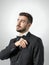 Young groom in tuxedo with bow tie putting plastic comb in his suit pocket.