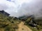 A young group of international hikers, led by their local Inca guide, navigate the Andes mountains through the clouds