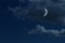 Young growing moon in night sky with clouds