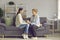 Young grown daughter and old senior mother holding hands sitting on home sofa