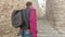 A young guy with a backpack, a tourist, leads the girl behind him, holding her hand along the medieval street in Girona, Spain.