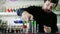 Young guy barman prepares vivid drink and slowly pouring bright scotch from bottle into glass with alcohol on counter on