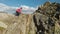 A young guy with a beard, a mountaineer in a cap and sunglasses, climbs a rocky ridge high in the mountains. Parkour in