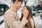 Young guy and beautiful girl kiss in a snowy park. Couple in sweaters.