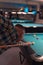 Young guy from behind play billard pool at night.