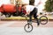 A young guy on a BMX bike, rides on the front wheel, braking with his foot