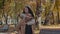 Young guy carries girl on back playful hispanic couple walking in autumn park girl laughing keep stretched out arms at