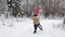 A young guy is circling his beloved girl in the snow forest, they are holding heart-shaped balloons in their hands.