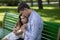 Young guy consoling his upset girlfriend on bench at park