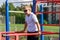 a young guy does push-ups on bars on a sports ground in the summer