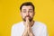 Young guy dressed casually isolated on yellow background, having put hands together in prayer or meditation, looking