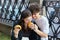 Young guy and a girl are holding hamburgers in their hands. the guy gives the girl a bite from his burger