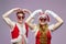 Young guy and girl in Santa costumes covered their eyes with Christmas ornaments