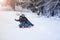Young guy and a girl ski tubing in the winter ride down a hill