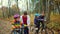 A young guy and a girl teach children to ride a bike in the autumn Park. Two little girls riding in safety helmets