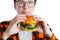 A young guy with glasses holding a fresh Burger. A very hungry student eats fast food. Hot helpful food. The concept of gluttony