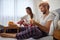 A young guy with his girlfriend in the bed peeling off an orange for a breakfast. Love, relationship, together