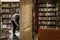 Young guy looking for books in the library with wooden bookcases. Knowledge and education. Blurred