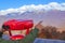 Young guy man points his finger at the mountain snow-capped peaks holding red binoculars for review and observation of panoramic