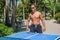 A young guy plays table tennis without shirts in a park on a background of palms in a tourist city in the summer.