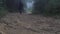 Young guy in raincoat jogging on wood trail during travel. Hiking man with backpack running in tropical wet forest. Male