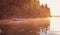 A young guy rides a boat on a lake during a golden sunset. Rower at sunset. Unity with nature concept