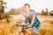 A young guy in a shirt and naked torso sits on a bicycle in headphones and listens to music outdoors, nature, field outside city