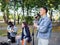 Young guy sings songs and plays guitar on a jeans jacket in a park on a natural background.