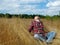 Young guy is sitting in the autumn grass. Relaxation and tourism in nature.