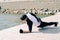 A young guy in sports black clothes on a pier near the lake doing sports exercises in the plank on a Sunny spring day, healthy