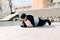 A young guy in sports black clothes on a pier near the lake doing sports exercises in the plank on a Sunny spring day, healthy