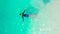 A young guy swims among Baby sharks - Ginglymostoma and Stingrays in the turquoise sea with white sand beach of Fulidhoo