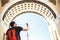 Young guy tourist with backpack taking mobile photo of historical archway in the palace square in St. Petersburg