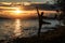 Young guy tourist jumps and enjoys a beautiful sunset over the lake. A midges fly around him, which glows in the rays