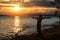 A young guy tourist spread his arms wide and enjoys a beautiful sunset over the lake. A midges fly around him, which glows in the