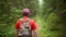 Young guy traveler walks along a trail in a dense dark forest, camera tracking