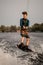 young guy wakeboarder holds rope in his hands and jumping on wave