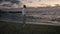 Young guy is walking on the beach and enjoys the evening seascape