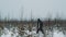 Young guy walking on snow covered prairie bushes on winter day