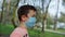 Young guy wearing medical mask in garden. Teen boy walking in mask outdoors