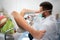 Young gynecologist putting gel on equipment to exam patient