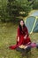 A young gypsy woman grills meat on the grill near the tent in the smoke of the fire. Horizontal photo