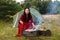 A young gypsy woman grills meat near the tent.