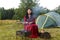 A young gypsy woman grills meat near the tent.